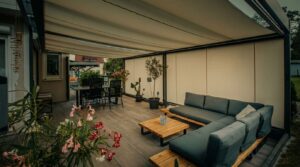 Beige Beschattung über einer Terrasse mit gepolstertem Sofa, Holztisch und stimmiger Privatsphäre für ein angenehmes Klima an warmen Tagen.