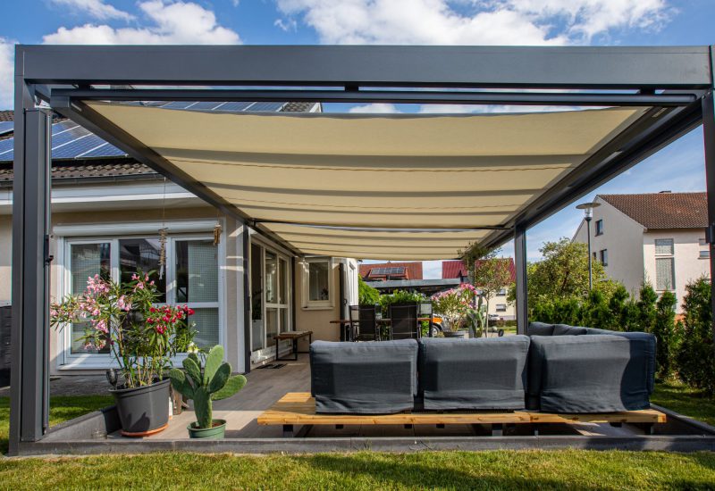 Moderne Aluminium-Überdachung mit robuster Konstruktion und geschützter Dachfläche, klare Linien und dezente LED-Elemente im Hintergrund.